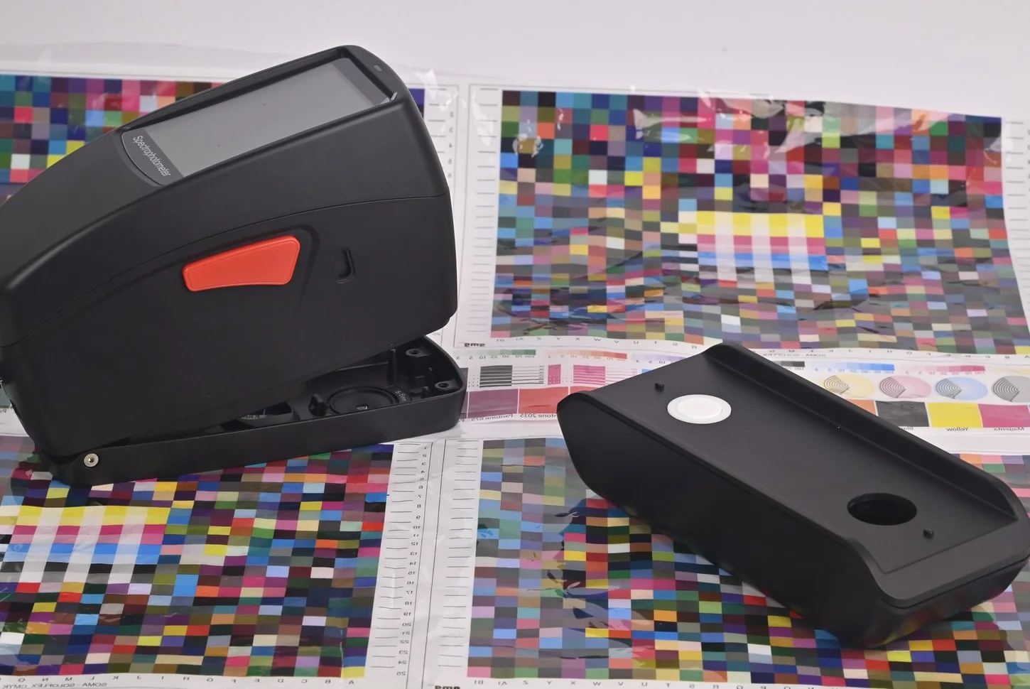 Espectrodensitómetro SpectroFit y su base de calibración apoyados sobre cartas de color CMYK impresas