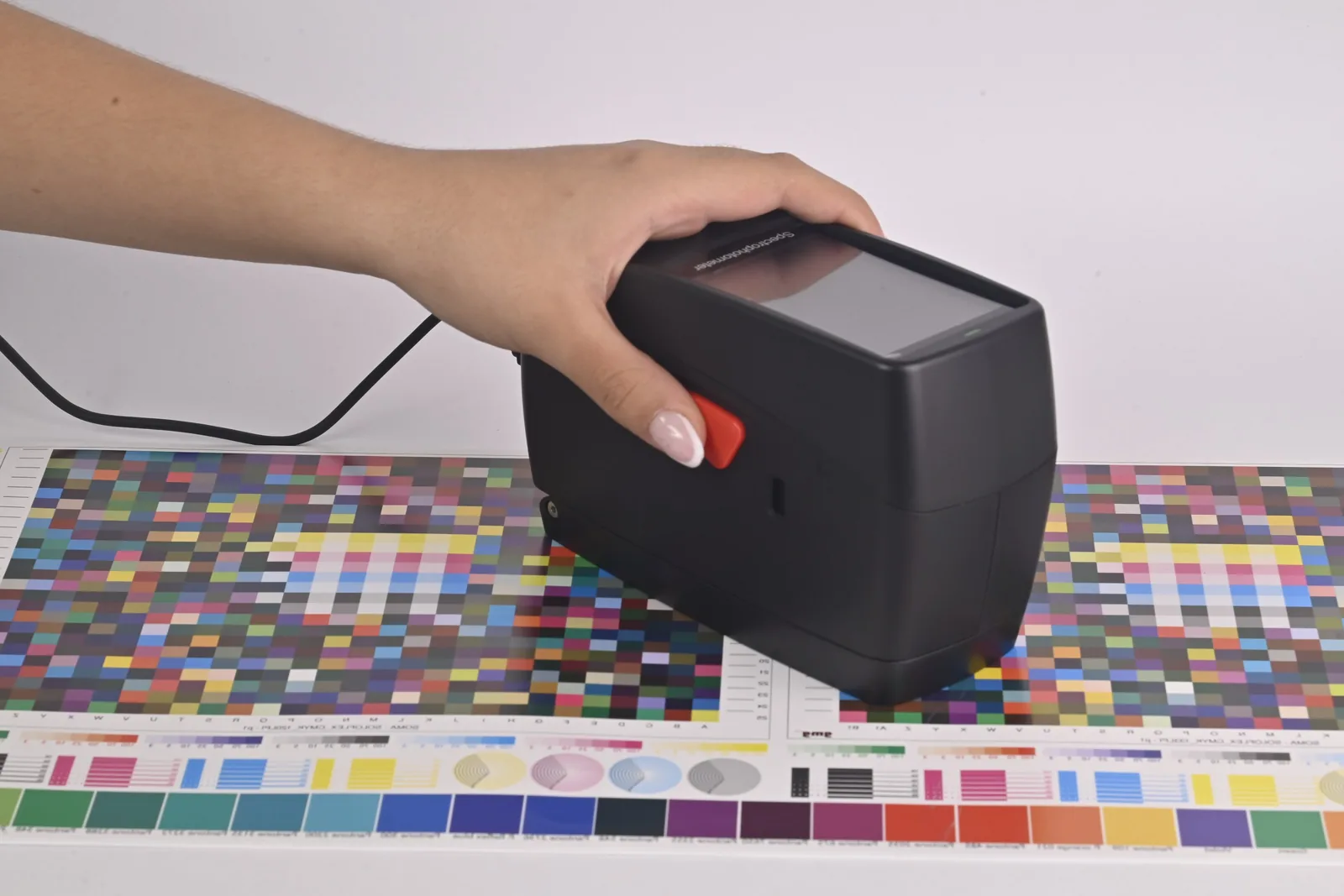 Operario sosteniendo el espectrodensitómetro SpectroFit sobre una carta de color impresa
