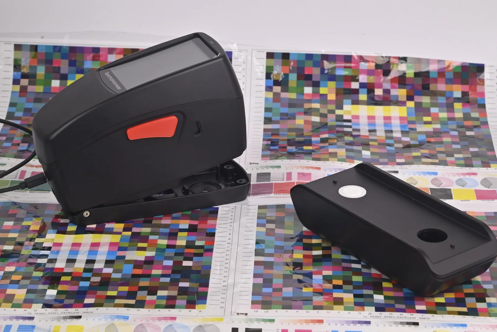 Espectrodensitómetro SpectroFit junto a su base de calibración sobre cartas de prueba CMYK impresas
